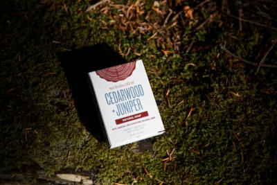 Schmidt's Cedarwood+Juniper natural bar soap box on a mossy ground in dark lighting
